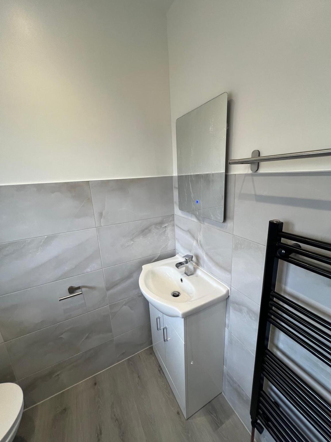 Vanity, mirror and black towel radiator