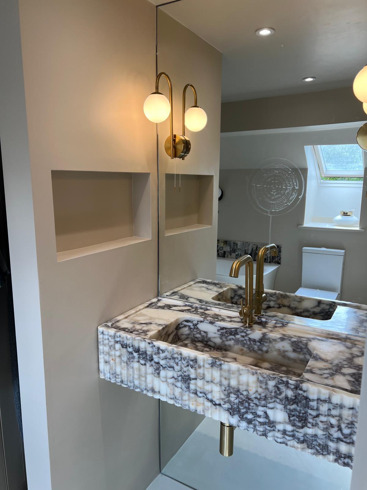 Sculpted stone basin with warm brass fittings