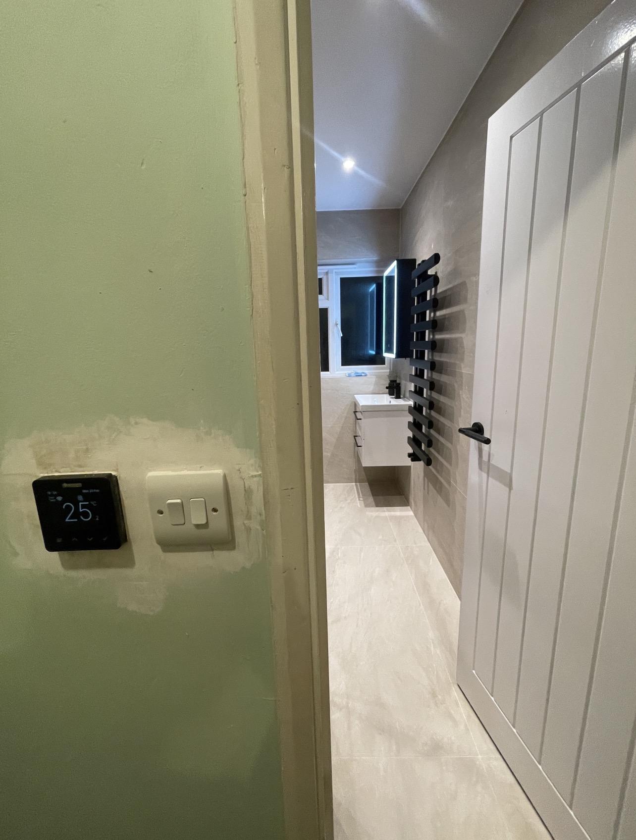 View from the doorway showing the underfloor heating thermostat and separate lighting switches