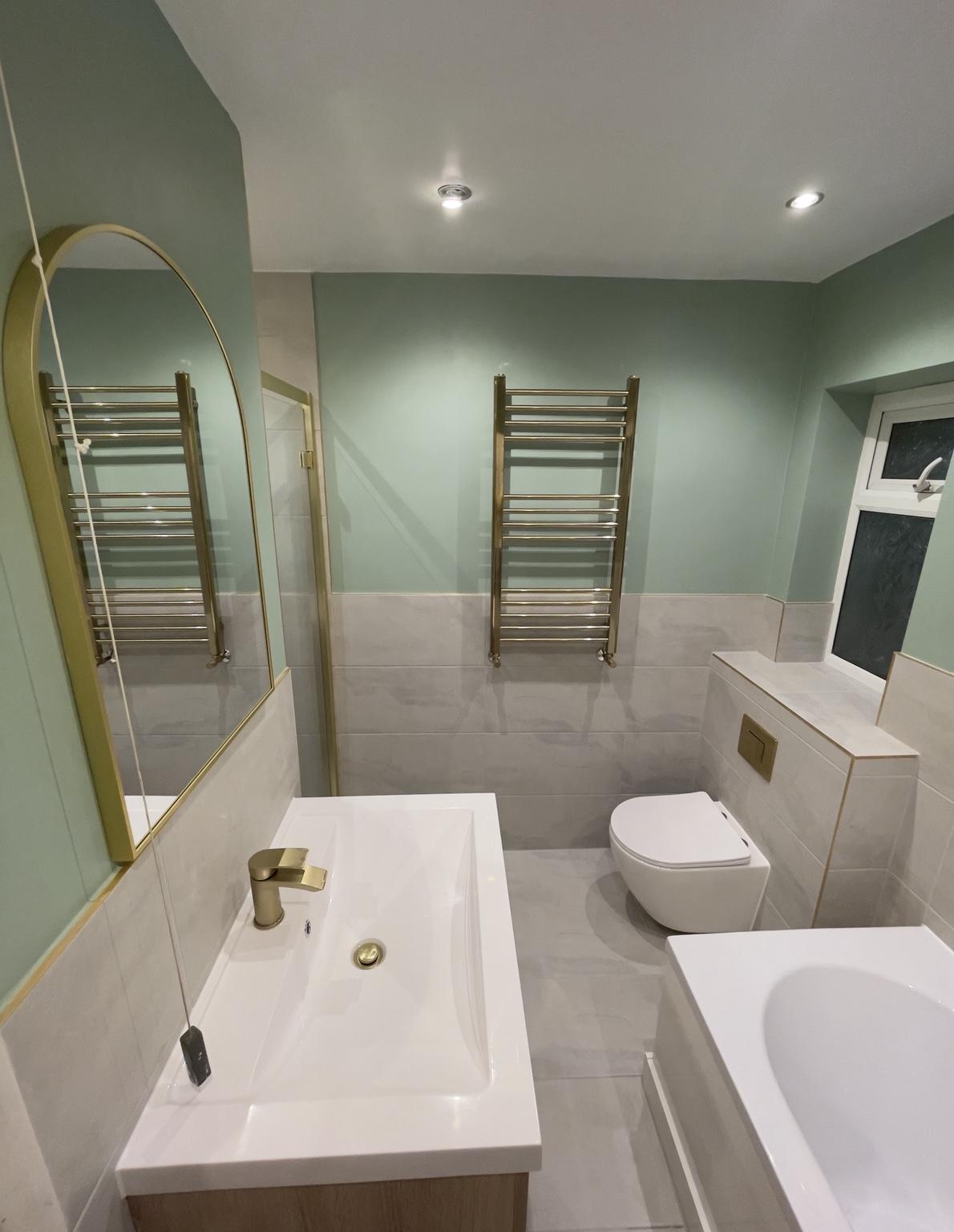 Sage green wall, arched mirror and gold taps