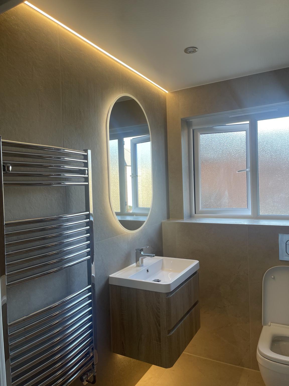 Warm LED glow beneath the floating vanity and around the oval mirror
